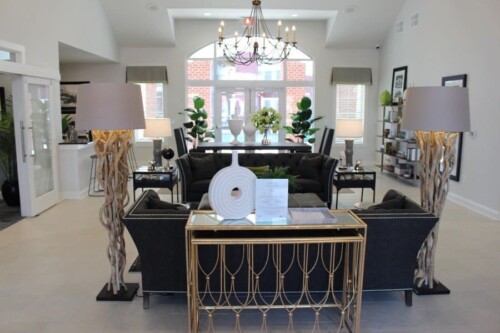 Clubhouse lounge with sofas and chandelier at Clairmont at Campostella Station Apartments