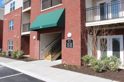 Apartment building entrance with green awning at Clairmont at Campostella Station Apartments