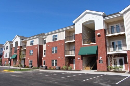 Brick apartment buildings with balconies and parking at Clairmont at Campostella Station Apartments